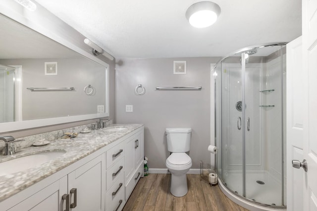 bathroom featuring hardwood / wood-style flooring, vanity, toilet, and a shower with shower door