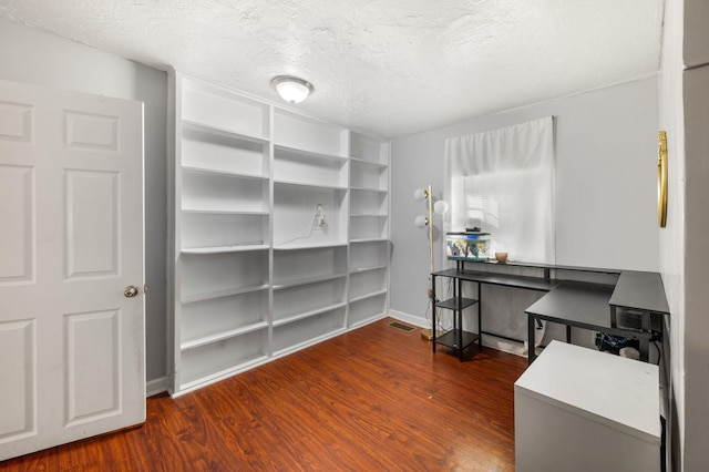 home office with dark hardwood / wood-style flooring and a textured ceiling