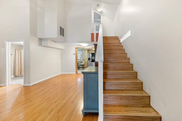 staircase with hardwood / wood-style flooring and a high ceiling