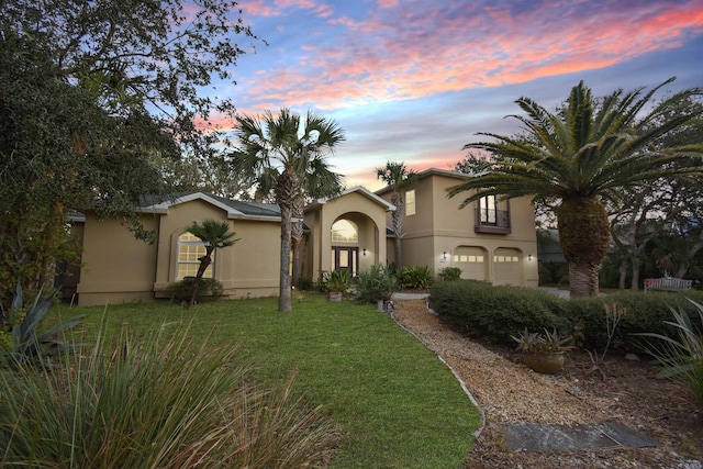 mediterranean / spanish house featuring a yard and a garage