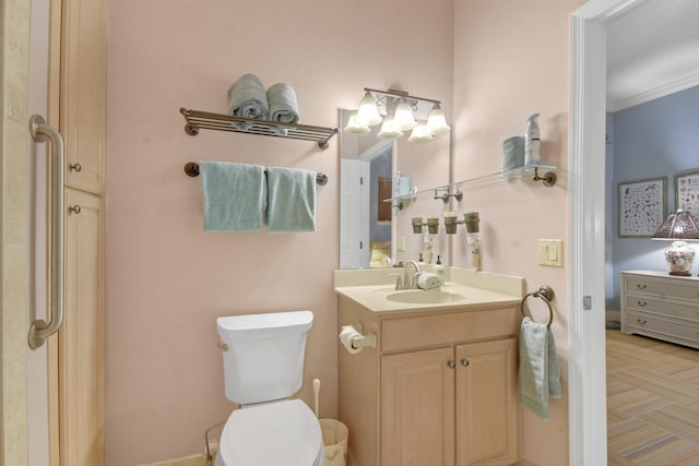 bathroom with toilet, vanity, and ornamental molding