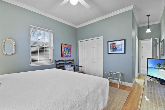 bedroom featuring ceiling fan, a closet, crown molding, and light hardwood / wood-style flooring