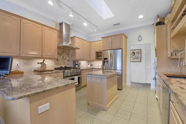 kitchen with a skylight, wall chimney exhaust hood, light stone counters, a kitchen island, and appliances with stainless steel finishes