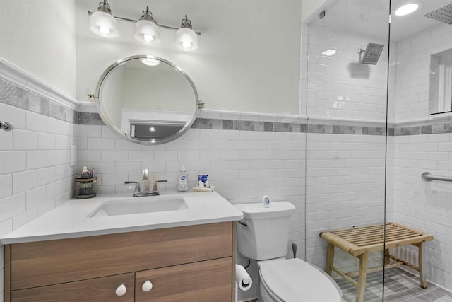 bathroom featuring a tile shower, vanity, tile walls, and toilet