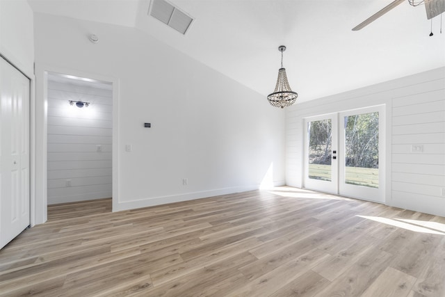 interior space featuring lofted ceiling, visible vents, a ceiling fan, wood walls, and light wood-type flooring