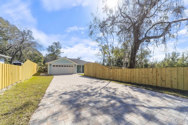 view of front of home featuring a garage, decorative driveway, and fence