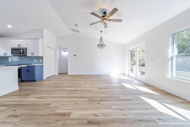 kitchen with open floor plan, stainless steel microwave, vaulted ceiling, and light wood-style flooring