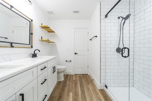 bathroom with visible vents, a sink, a tile shower, and toilet