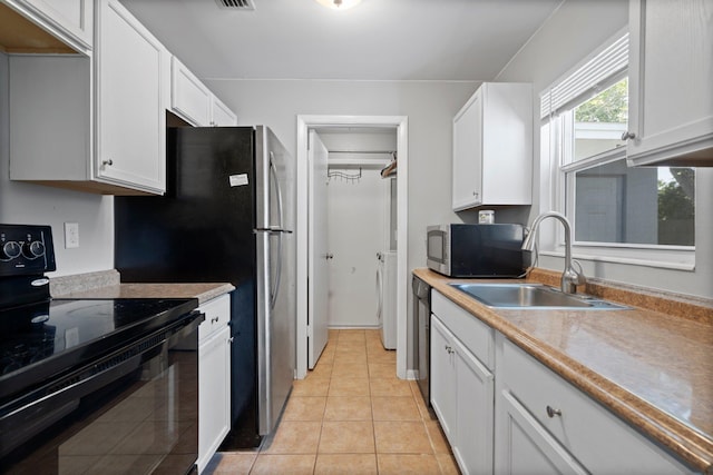82 Andora St, Saint Augustine, FL 32086 - kitchen with white cabinetry, black appliances, light countertops, a sink, and washer / dryer