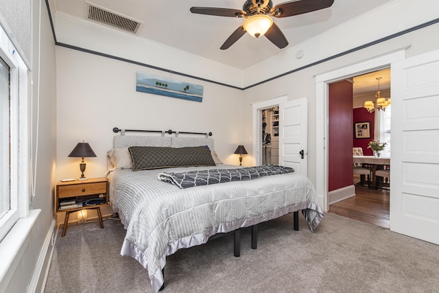 60 Saragossa St, Saint Augustine, FL 32084 - carpeted bedroom with a walk in closet, a closet, visible vents, ornamental molding, and ceiling fan with notable chandelier
