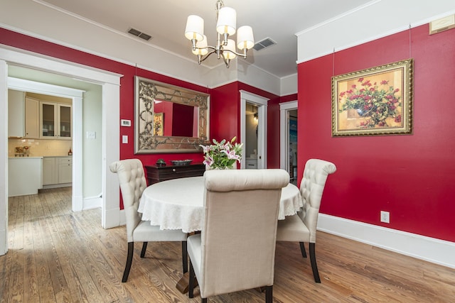 60 Saragossa St, Saint Augustine, FL 32084 - dining space featuring ornamental molding, wood finished floors, visible vents, and an inviting chandelier