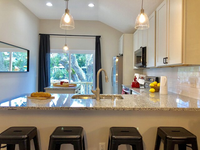 3877 Laurel St, Saint Augustine, FL 32084 - kitchen with stainless steel appliances, a sink, decorative backsplash, white cabinetry, and light stone counters
