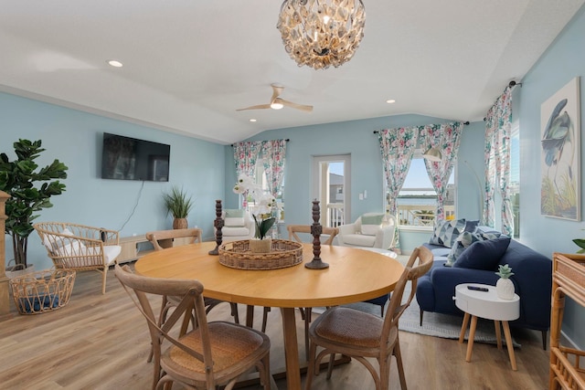 dining room featuring ceiling fan with notable chandelier, lofted ceiling, and light wood-type flooring