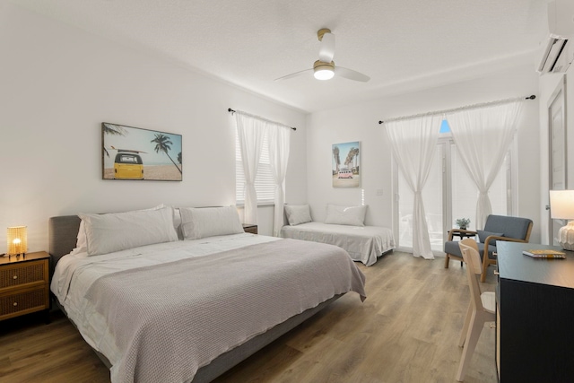 bedroom featuring a wall mounted air conditioner, ceiling fan, and wood-type flooring