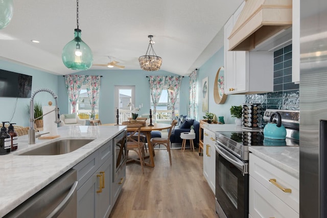 kitchen with white cabinets, sink, stainless steel appliances, and hanging light fixtures