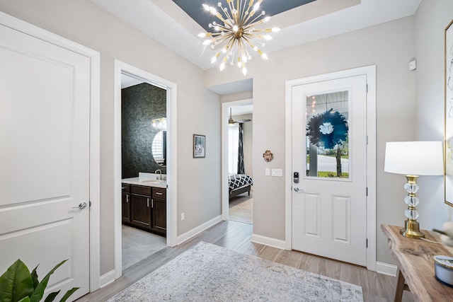 entrance foyer with a chandelier, light wood-type flooring, and sink