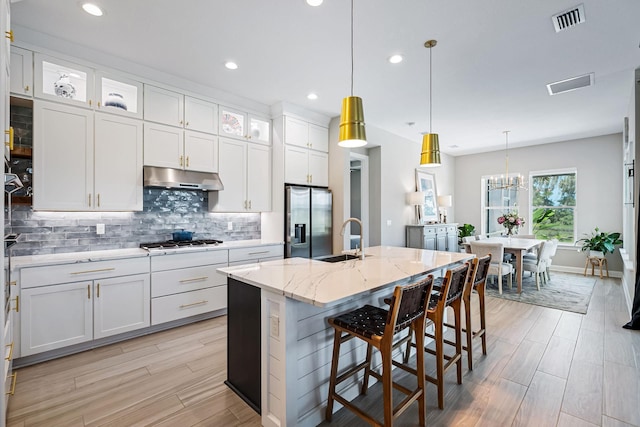 kitchen with white cabinetry, a kitchen island with sink, pendant lighting, and appliances with stainless steel finishes