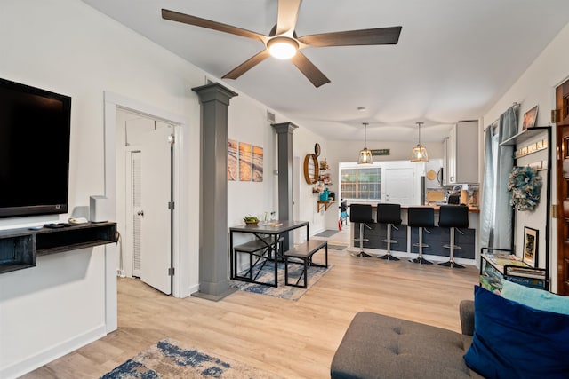 living room featuring ceiling fan, light hardwood / wood-style flooring, and ornate columns