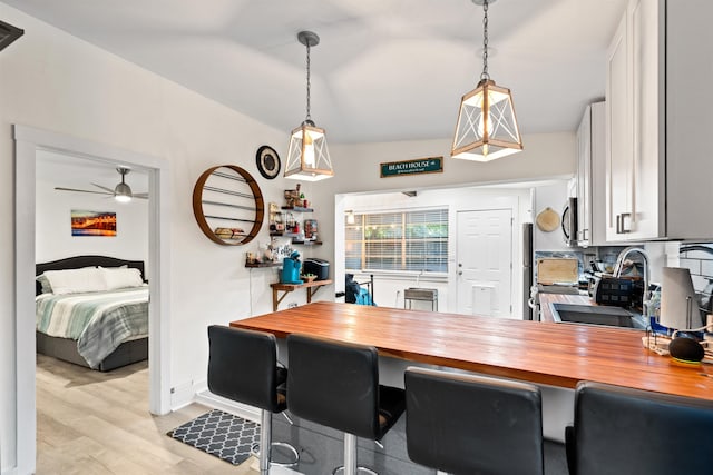 interior space featuring vaulted ceiling, sink, ceiling fan, and light hardwood / wood-style flooring