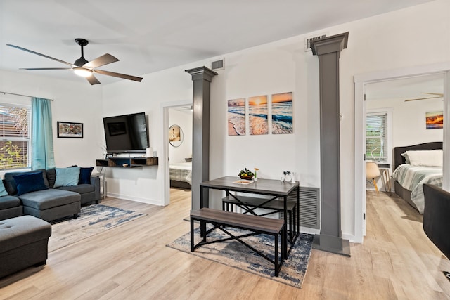 living room with light hardwood / wood-style flooring, decorative columns, and ceiling fan