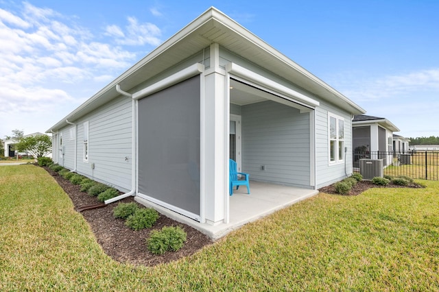 view of side of property featuring central AC unit, a lawn, and a patio area