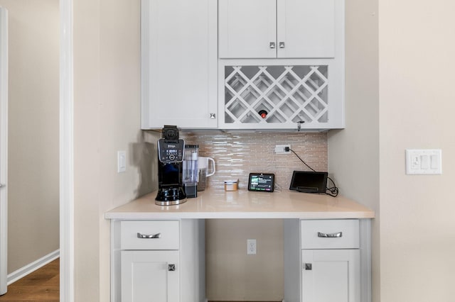 bar featuring decorative backsplash, hardwood / wood-style flooring, and white cabinetry