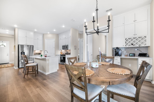 dining area featuring light hardwood / wood-style flooring, a chandelier, and sink