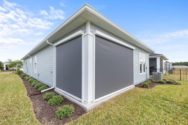 view of side of home featuring cooling unit and a lawn