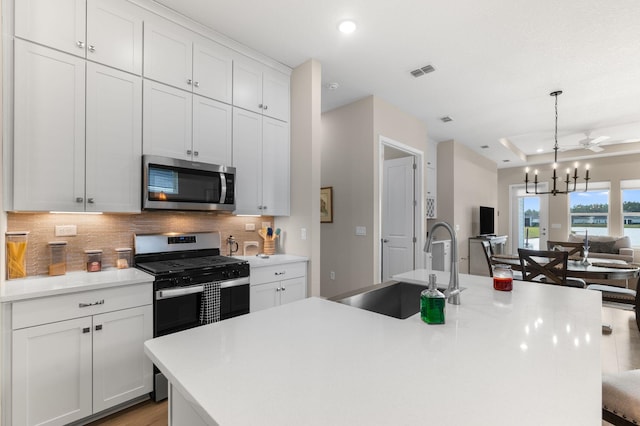 kitchen with stainless steel appliances, an inviting chandelier, and an island with sink