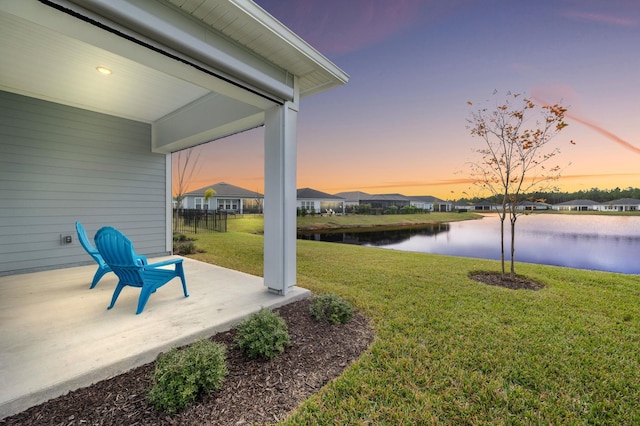 yard at dusk with a patio and a water view