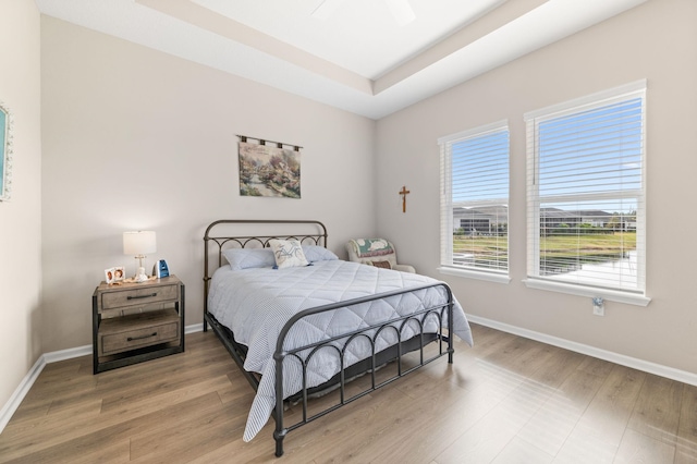 bedroom featuring hardwood / wood-style flooring, ceiling fan, and a tray ceiling