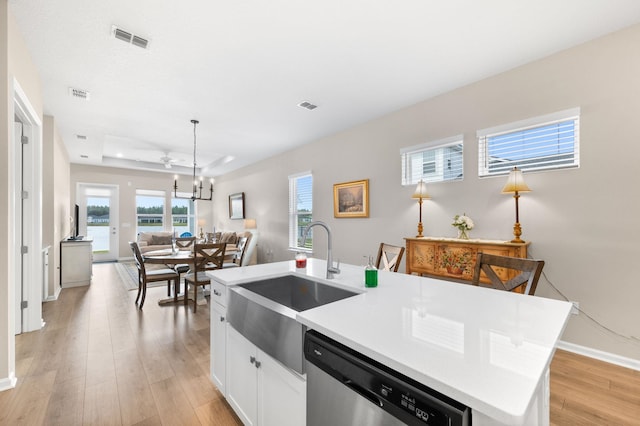 kitchen with sink, white cabinets, dishwasher, a tray ceiling, and a kitchen island with sink