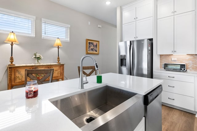 kitchen featuring white cabinets, appliances with stainless steel finishes, backsplash, and sink