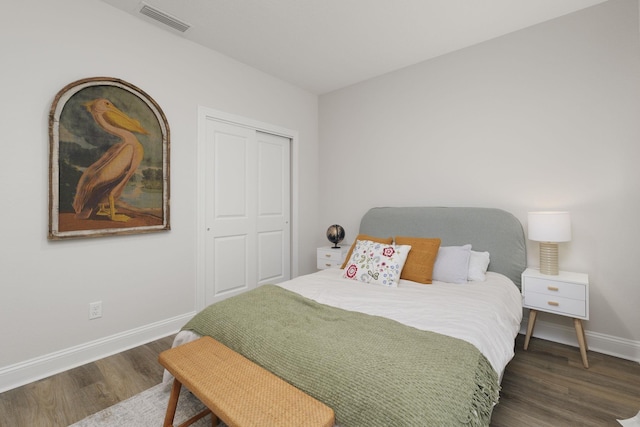 bedroom with wood finished floors, baseboards, and a closet