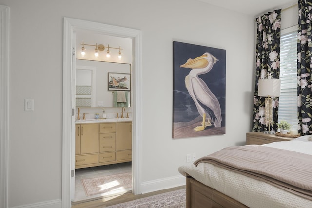bedroom featuring baseboards, ensuite bathroom, and wet bar