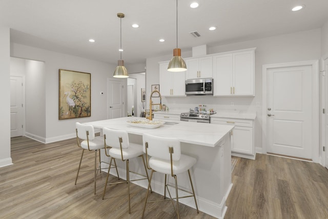 kitchen featuring appliances with stainless steel finishes, light wood-type flooring, a sink, recessed lighting, and baseboards