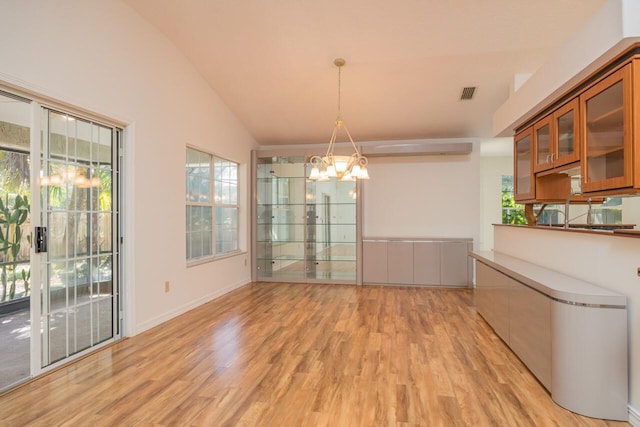 unfurnished dining area with lofted ceiling, light wood finished floors, visible vents, and a chandelier