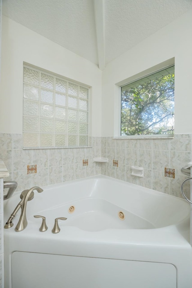 bathroom with a tub with jets and a textured ceiling