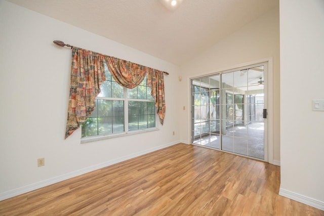 unfurnished room featuring lofted ceiling, light wood-style flooring, and baseboards