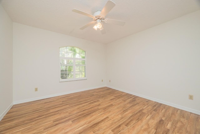 empty room with light wood finished floors, a ceiling fan, and baseboards