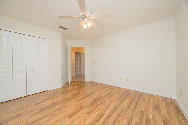 unfurnished bedroom with light wood-style flooring, a closet, visible vents, and baseboards