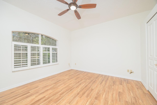 spare room featuring light wood-type flooring, a ceiling fan, and baseboards