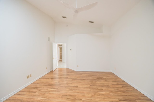 unfurnished room featuring light wood finished floors, visible vents, baseboards, and vaulted ceiling