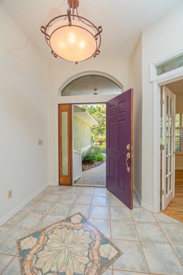 foyer entrance with plenty of natural light, baseboards, and light tile patterned floors