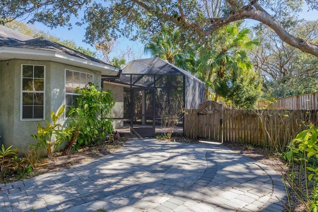 view of patio with fence, a gate, and a lanai