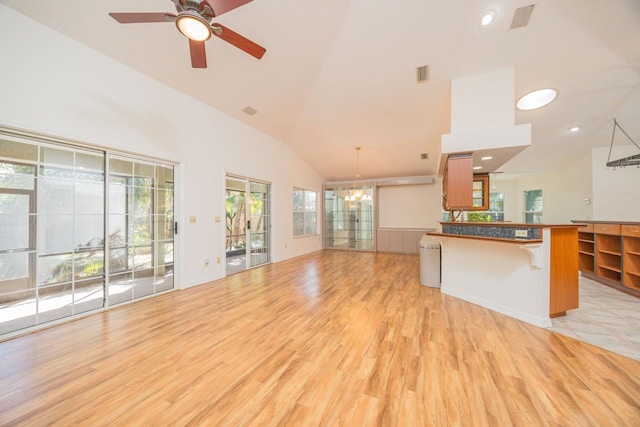 unfurnished living room with high vaulted ceiling, light wood-style flooring, recessed lighting, ceiling fan with notable chandelier, and visible vents