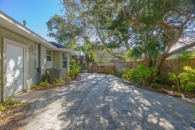 exterior space with a lanai, fence private yard, and central air condition unit