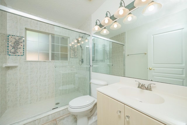 full bath with vanity, tile patterned flooring, a tile shower, and toilet