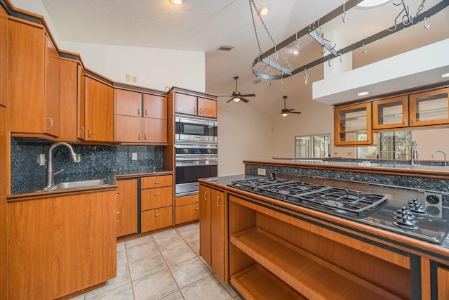 kitchen featuring light tile patterned floors, a sink, appliances with stainless steel finishes, tasteful backsplash, and dark countertops