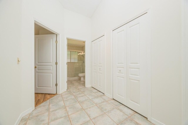 corridor with light tile patterned floors and baseboards